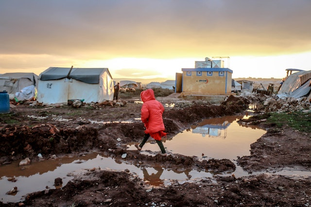 Unrecognizable girl walking on mud against shack houses - forced human migration
