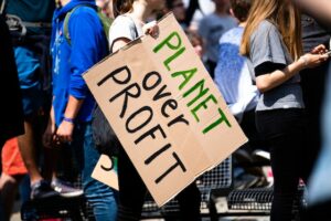 woman holding planet over profit sign.