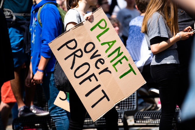 woman holding planet over profit sign.